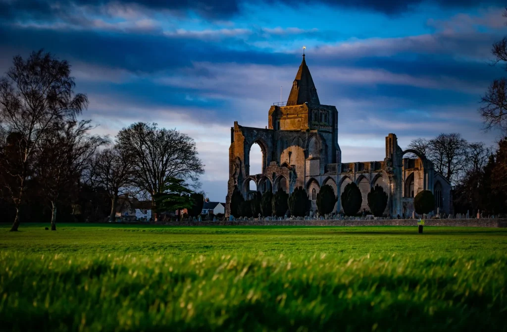 Historic Crowland Abbey ruins viewed from a field, evoking reliability and established service, reflecting KOZ