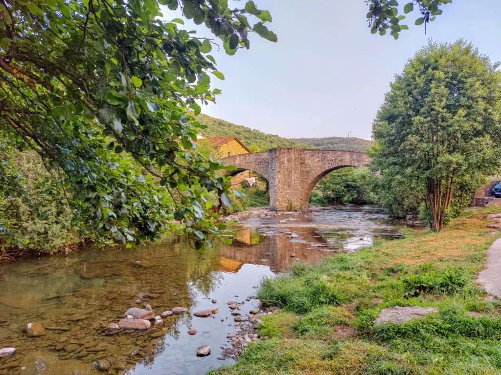 Scenic stone bridge spanning a river with lush trees and greenery, symbolizing reliable plumbing and