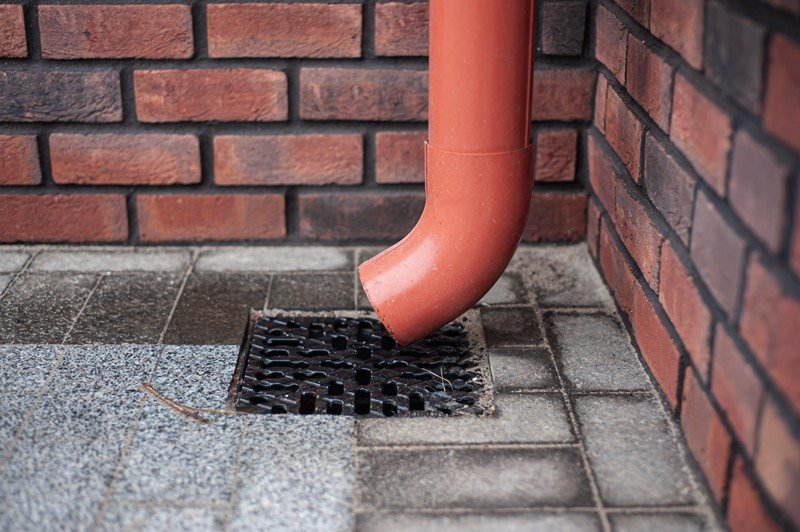 Red drainpipe and gully illustrating drainage solutions and pipe maintenance.