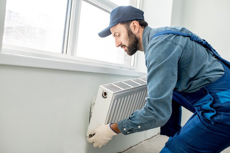 Heating engineer inspecting a radiator during central heating system repair and maintenance in London. The